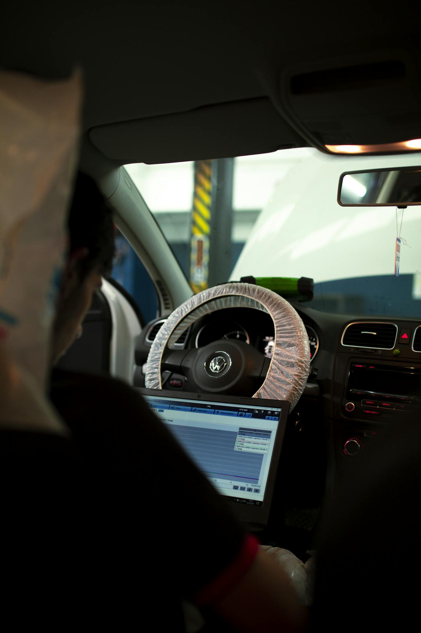 Mechanic inside car using laptop for diagnostics. Ideal for automotive and technology themes.